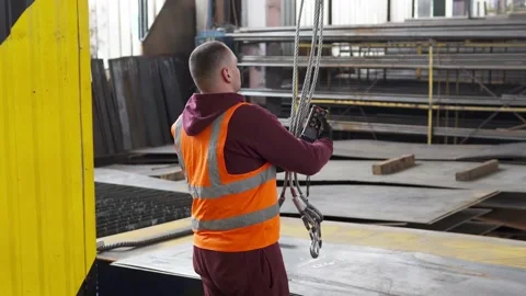A worker moves metal parts using an overhead crane. Stock Footage 275895042