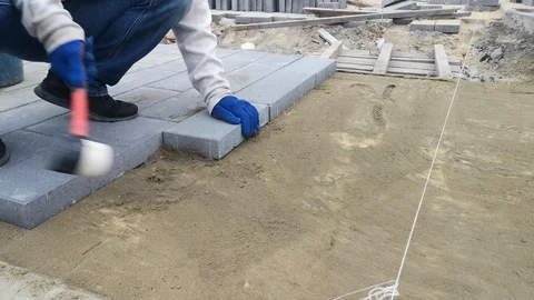 A worker moves a row of paving slabs, knocking on them with a rubber hammer - 8s Stock Footage