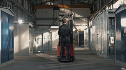 Worker moves through the workshop while standing on automated trolley - loader Stock Footage 265509356