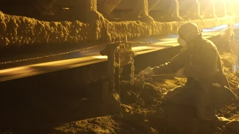 Worker moving coal ashes from the conveyor belt at an electricity plant with Stock Footage 121811139