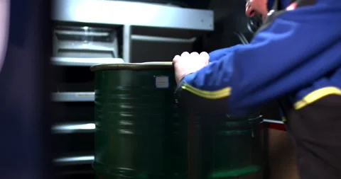 Worker Moving Large Green Steel Drum, Dark Industrial Warehouse, Handheld Shot Stock Footage 340324468