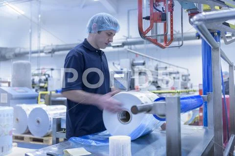 Worker Moving Roll Of Packaging In Food Packaging Printing Factory