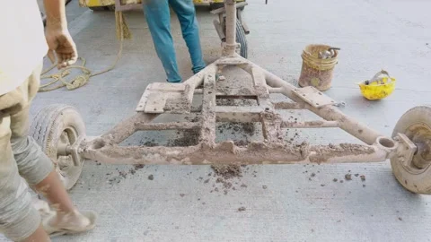 Worker moving a rusty metal frame of an old vehicle with wheels on concrete.. Stock Footage 262026059
