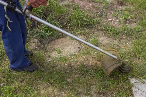 Worker mowing the grass with gas string trimmer Stock Photos