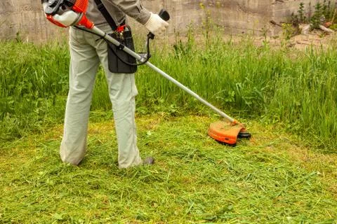 Worker mowing grass with a trimming machine Stock Photos