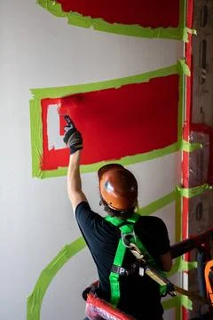 A worker with NASAs Exploration Ground Systems (EGS) applies bright red p.. Fotos de archivo
