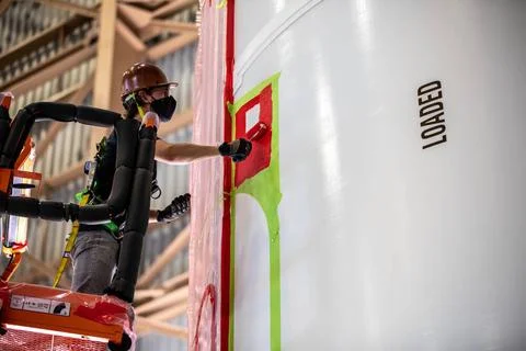 A worker with NASAs Exploration Ground Systems (EGS) applies bright red p.. Fotos de archivo