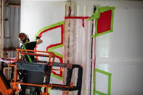 A worker with NASAs Exploration Ground Systems (EGS) applies bright red p.. Fotos de archivo