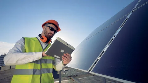 A worker near solar panels, close up. Engineer working on his tablet next to Stock Footage