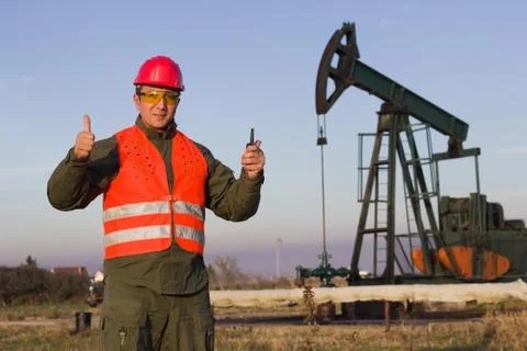 Worker on an oil pump keeps the thumbs up and smiling Stock Photos