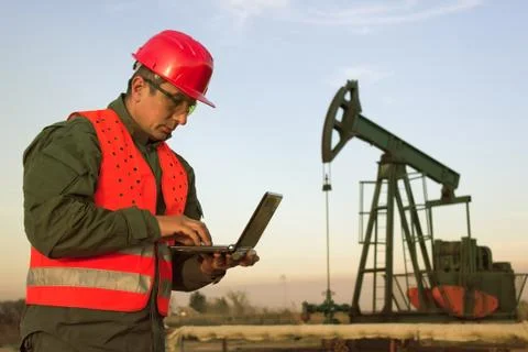 Worker on an oil rig using a laptop Stock Photos