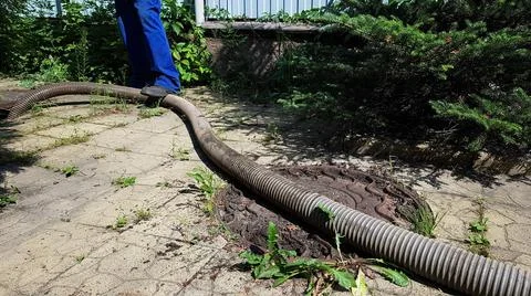 The worker opened the sewer hatch and inserted a hose for cleaning the septic Stock Photos