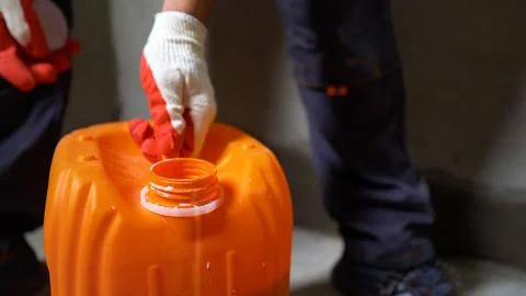 Worker opening orange plastic jerrycan with protective gloves Stock Photos