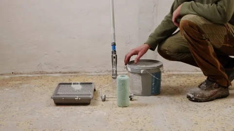 Worker opening paint bucket and preparing roller for renovation Stock Footage 325743281