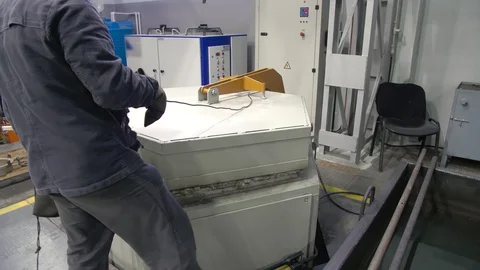 A worker opens the door of the tempering furnace. Quenching of steel billets Stock Footage 128802201