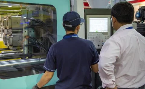 Worker operate injection molding press machine Stock Photos