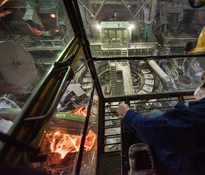 Worker operates in the cabin of a cargo crane at the steel mill Stock Photos