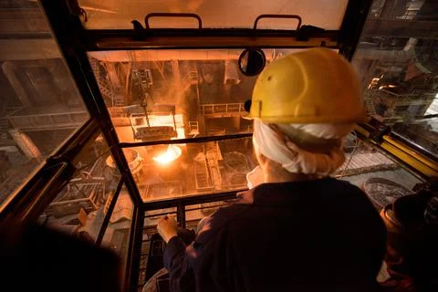 Worker operates in the cabin of a cargo crane at the steel mill Stock Photos