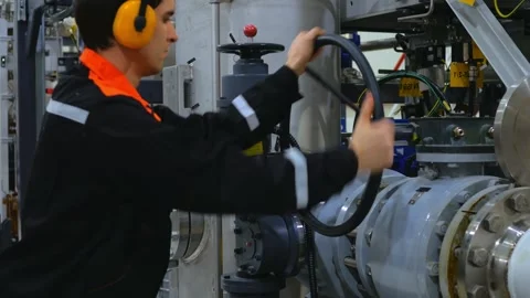 Worker operates crane handle to close pipeline. Industrial worker wearing Stock-Footage 285653109