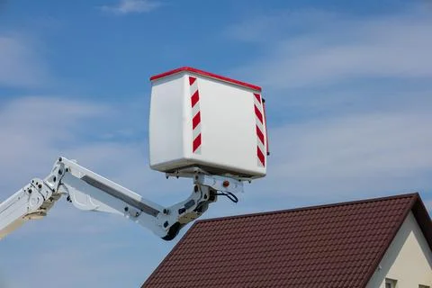 A worker operates an elevated platform to perform maintenance tasks on a re.. Stock Photos