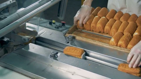 A worker operates a half automatic pastry wrapper. Video stock 85457138