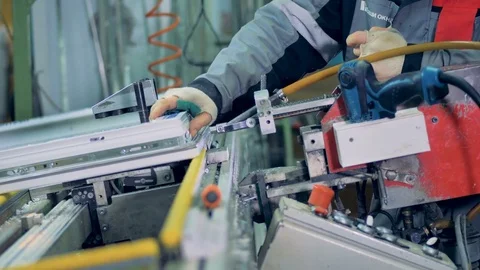 A worker operates a pneumatic screwing unit on window frames. Stock Footage 84411277
