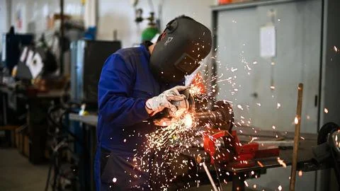 Worker operating an angle grinder and making lots of sparks Stock Photos