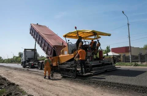 Worker operating asphalt paver machine during road construction and repairing Stock Photos