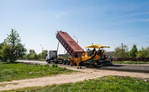 Worker operating asphalt paver machine during road construction and repairing Stock Photos