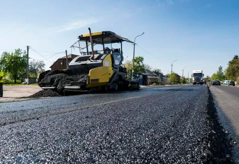 Worker operating asphalt paver machine during road construction and repairing Stock Photos