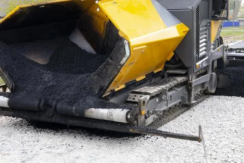 Worker operating asphalt paver machine during road construction and repairing Stock Photos