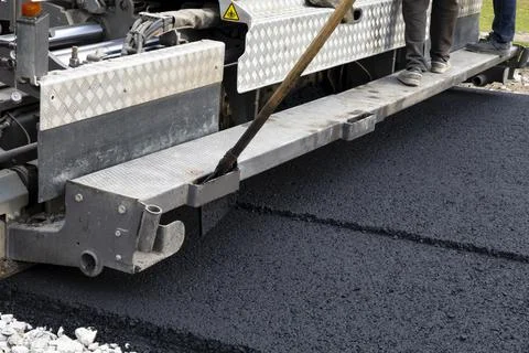 Worker operating asphalt paver machine during road construction and repairing Stock Photos