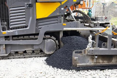 Worker operating asphalt paver machine during road construction and repairing Stock Photos