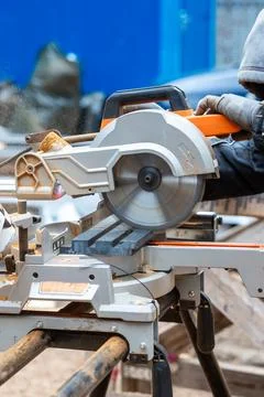 Worker Operating Circular Saw at Construction Site with Blue Wall Stock Photos