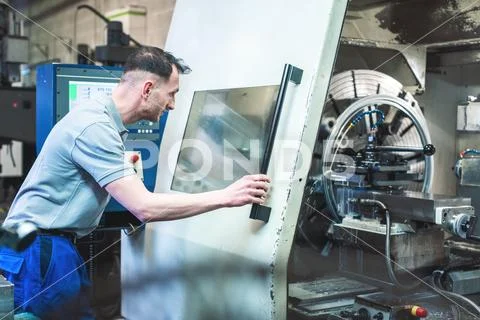 Worker operating a CNC lathe in factory Stock Photos