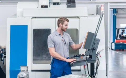 Worker operating computer-controlled machine tool Stock Photos