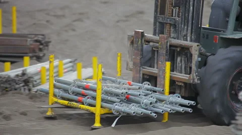 Worker operating forklift to move metalic pipes Stock Footage 56884190