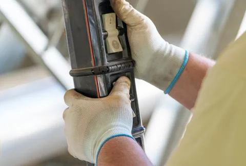 Worker operating a hoist crane control panel with protective gloves in an Stock Photos