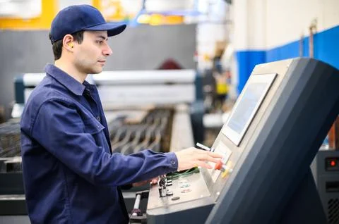 Worker operating a machine in a factory Stock Photos