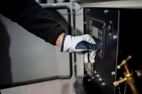 Worker operating machinery control interface with gloved hand Stock Photos