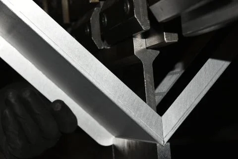 Worker operating metal press machine at workshop. Stock Photos