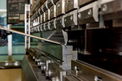 Worker operating metal press machine at workshop. Stock Photos