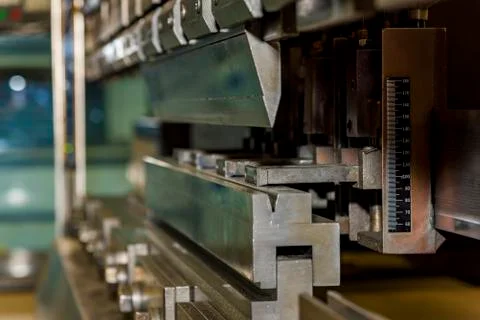 Worker operating metal press machine at workshop. Stock Photos