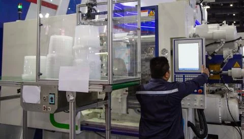 Worker operating plastic injection molding machine Stock Photos