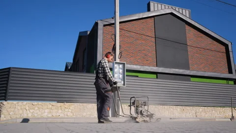 Worker Operating Plate Compactor on Pavement near Townhouse Stock-Footage 297789100