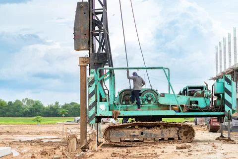 Worker operating a tracked pile driver machine to install ground foundation.. Stock Photos