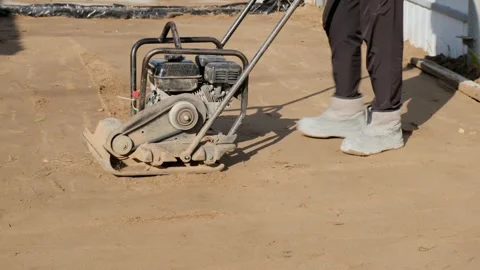 Worker operating vibration ramming machine for compaction of soil at a Stock Footage 285929300
