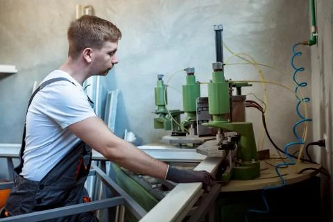 Worker operating welding machine in factory. Stock Photos