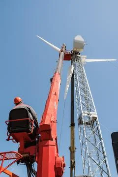 Worker operator of aerial platform at workplace. Installation of wind generator Stock Photos