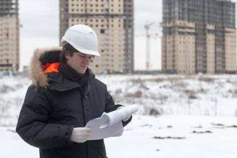 Worker or engineer holding drawing in hands and reading it on background of new Stock Photos